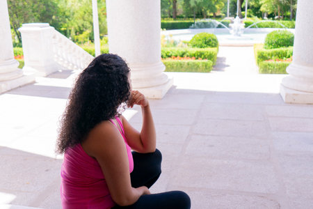 Young black woman sitting on the stairs in a park and looking awayの写真素材
