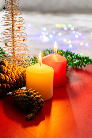 Christmas decoration with burning candles and pine cones on a red background.の写真素材