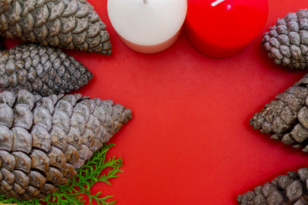 Christmas background with pine cones and candles on red background. Top viewの写真素材