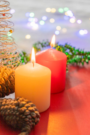 Christmas candles with christmas tree and colorful lights on the background.の写真素材
