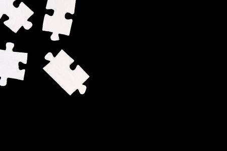 Pieces of white jigsaw puzzle isolated on black background. Copy space.の写真素材