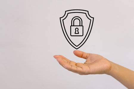 Hand holding a padlock with a shield on a white background.の写真素材
