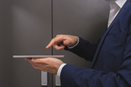 Close-up of businessman using digital tablet while standing in locker roomの写真素材