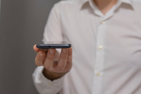 Man using mobile smart phone on gray background. Close up of male hand holding smartphone.の写真素材