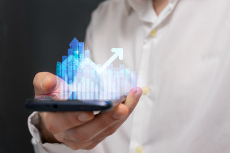 Businessman holding a smartphone in his hands with a graph on the screenの写真素材