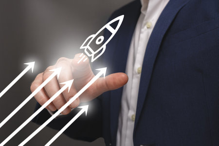 Businessman drawing a rocket on a touch screen interface with his fingersの写真素材