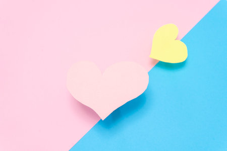 Two hearts, one pink and one yellow, on a pink and blue background, Valentine's Day background. Valentine's Day conceptの写真素材