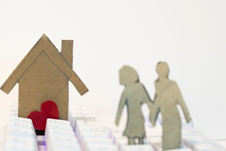 Paper house with red heart and family on white background.の写真素材