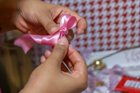Hands of a woman tying a pink ribbon on a gift boxの写真素材