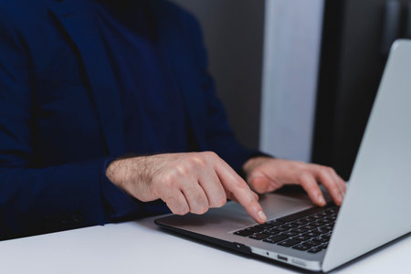 Businessman working on laptop in office. Close up of male hands typing on laptop keyboard.の写真素材
