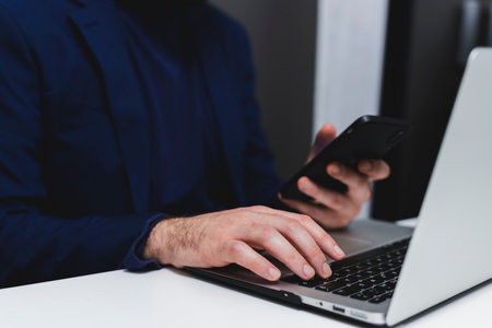 Cropped image of businessman using mobile phone while sitting at desk in officeの写真素材