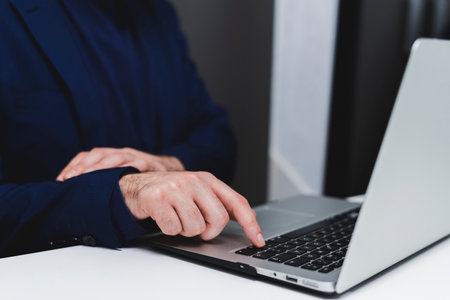 Close-up of male hands typing on laptop keyboard in office.の写真素材