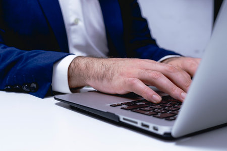 Businessman working on laptop at office. Closeup of male hands typing on laptop keyboard.の写真素材