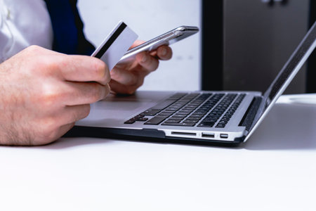 Man holding a credit card and using a laptop for online shopping.