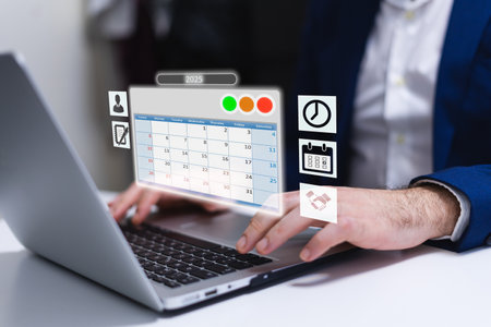 Businessman using a laptop in an office environment with calendar and iconsの写真素材