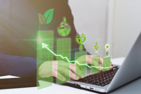 Businessman using laptop with green business graph and light bulb on screenの写真素材