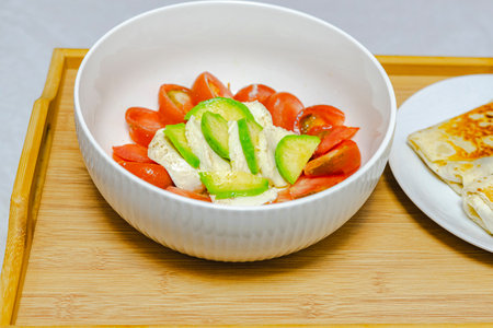 Salad with tomato, cucumber and mozzarella in a white bowlの写真素材