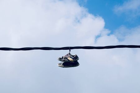 sneakers hanging in the cable in the streetの写真素材