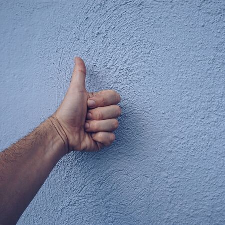 hand making ok gesture on the blue wall
