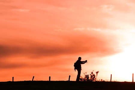 people taking photos in the meadow, sunset in spring seasonの写真素材