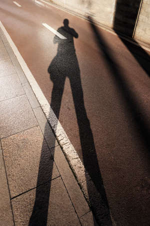 man photographing his shadow on the groundの写真素材