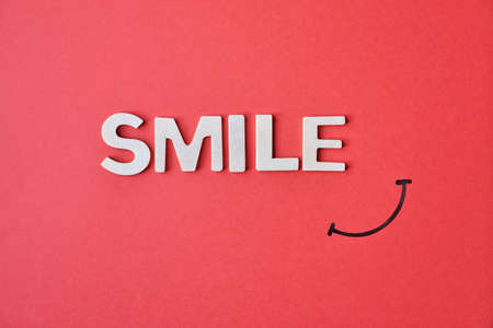 smile wooden letters on the red background, be happyの写真素材