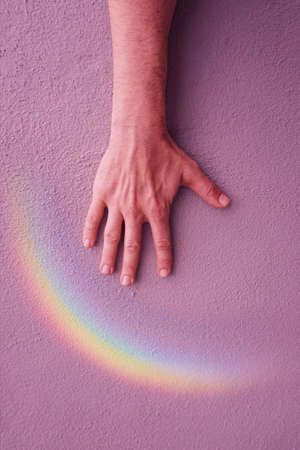 hand with a rainbow on the pink wall. gay prideの写真素材