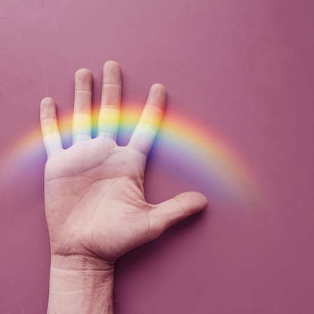 hand with a rainbow on the pink wall. gay prideの写真素材