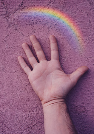 hand with a rainbow on the pink wall. gay prideの写真素材