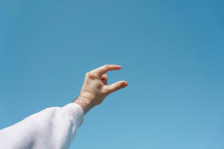 hand up in the air gesturing in the blue sky, blue backgroundの写真素材