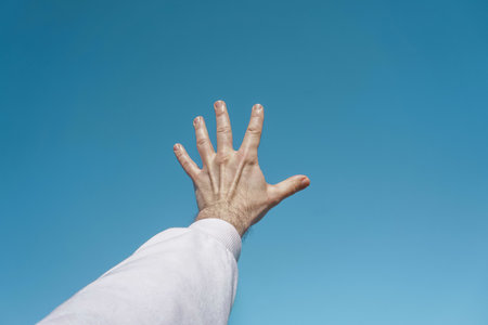 hand up in the air gesturing in the blue sky, blue background