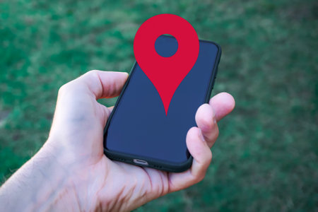 male hand holding a smart phone with red location symbol on the screen