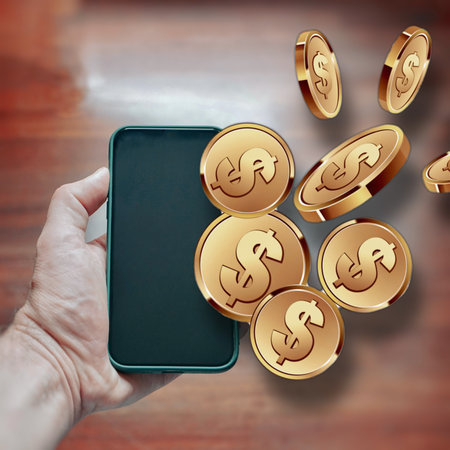 <p>hand holding a phone with coins on the screen</p>の写真素材