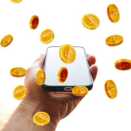 hand holding a phone with coins on the screenの写真素材