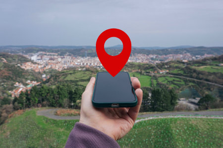 male hand holding a smartphone with a red pin on the background of the cityの写真素材
