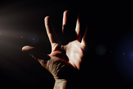 Man's hand on a black background with a beam of light.の写真素材