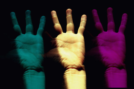 Hands of a child with different colors on a dark background.の写真素材