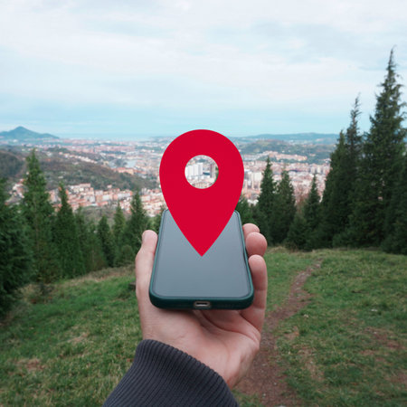 Hand holding mobile phone with red location pin on the top of the mountainの写真素材