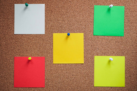Colorful sticky notes pinned to a cork board with copy space