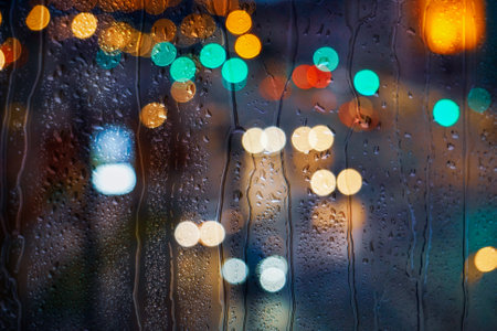 Rain drops on window with colorful bokeh lights background. Rainy day conceptの写真素材