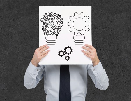 businessman holding poster with gears in form lampの写真素材