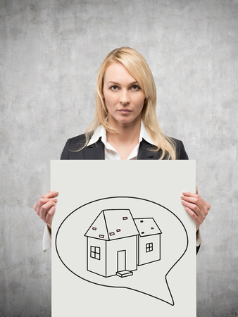 businesswoman holding poster with drawing house in speech bubblesの写真素材
