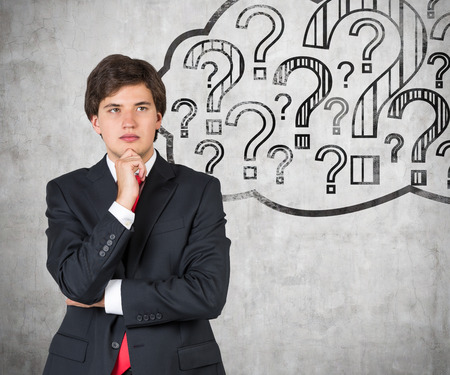 young businessman thinking and drawing question markの写真素材