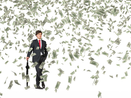 businessman standing with umbrella and falling dollarsの写真素材