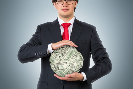 businessman holding money ball on a gray backgroundの写真素材