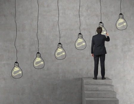 businessman drawing lamp on a concrete wallの写真素材