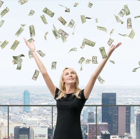 woman with hands up on falling dollars billsの写真素材