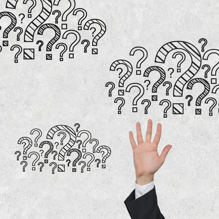 businessman reaches for the cloud of question marksの写真素材