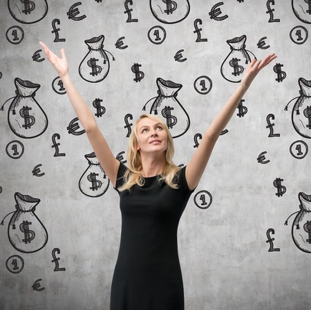 happy woman  and drawing money bags on wallの写真素材