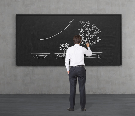businessman drawing growing tree on black deskの写真素材
